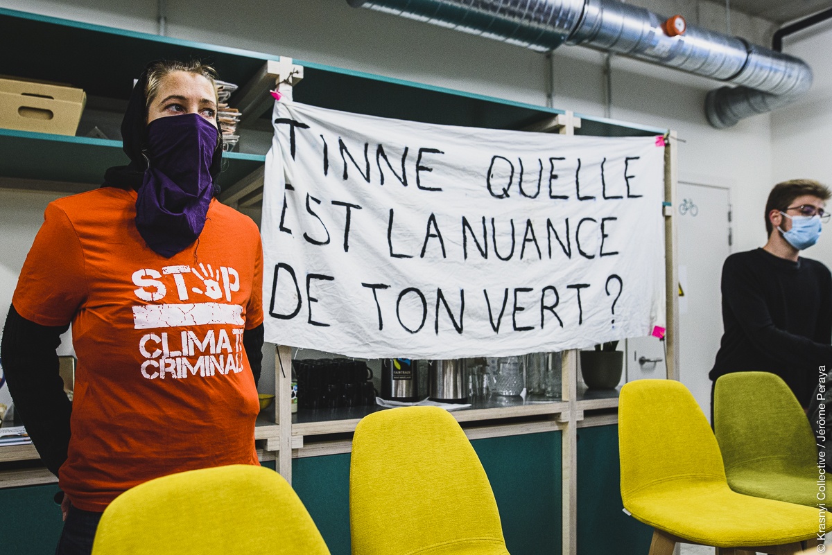 bezetting van kantoor ecolo-groen, activiste met t-shirt 'stop climate criminals' en spandoek 'tinne quelle est la nuance de ton vert?"