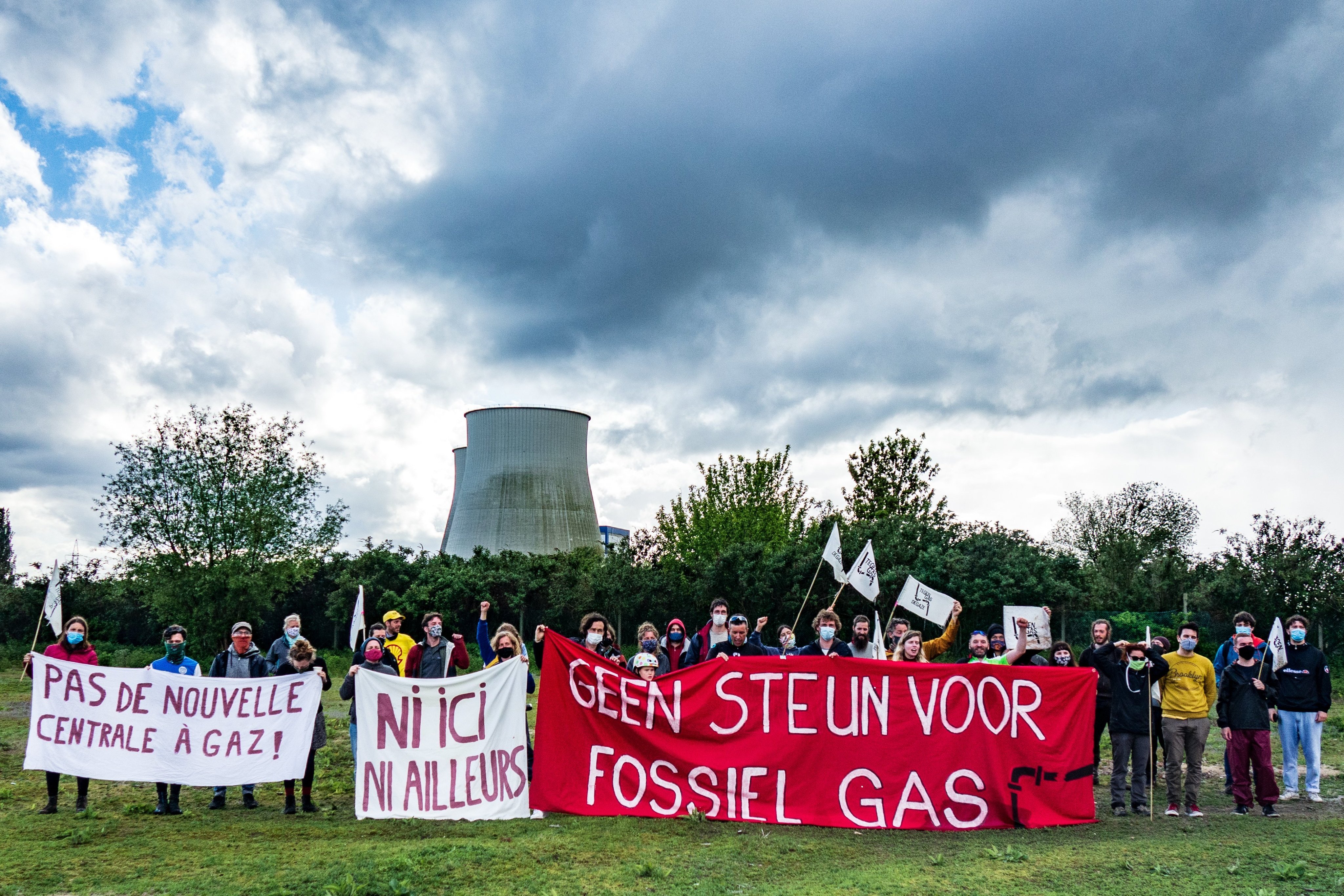 Circa dertig mensen met spandoeken "pas de nouvelle centrale à gaz", "ni ici ni alleurs", "geen steun voor fossiel gas" en vlaggetjes, op de achtergrond de koeltorens van de elektriciteitscentrales van Vilvoorde
